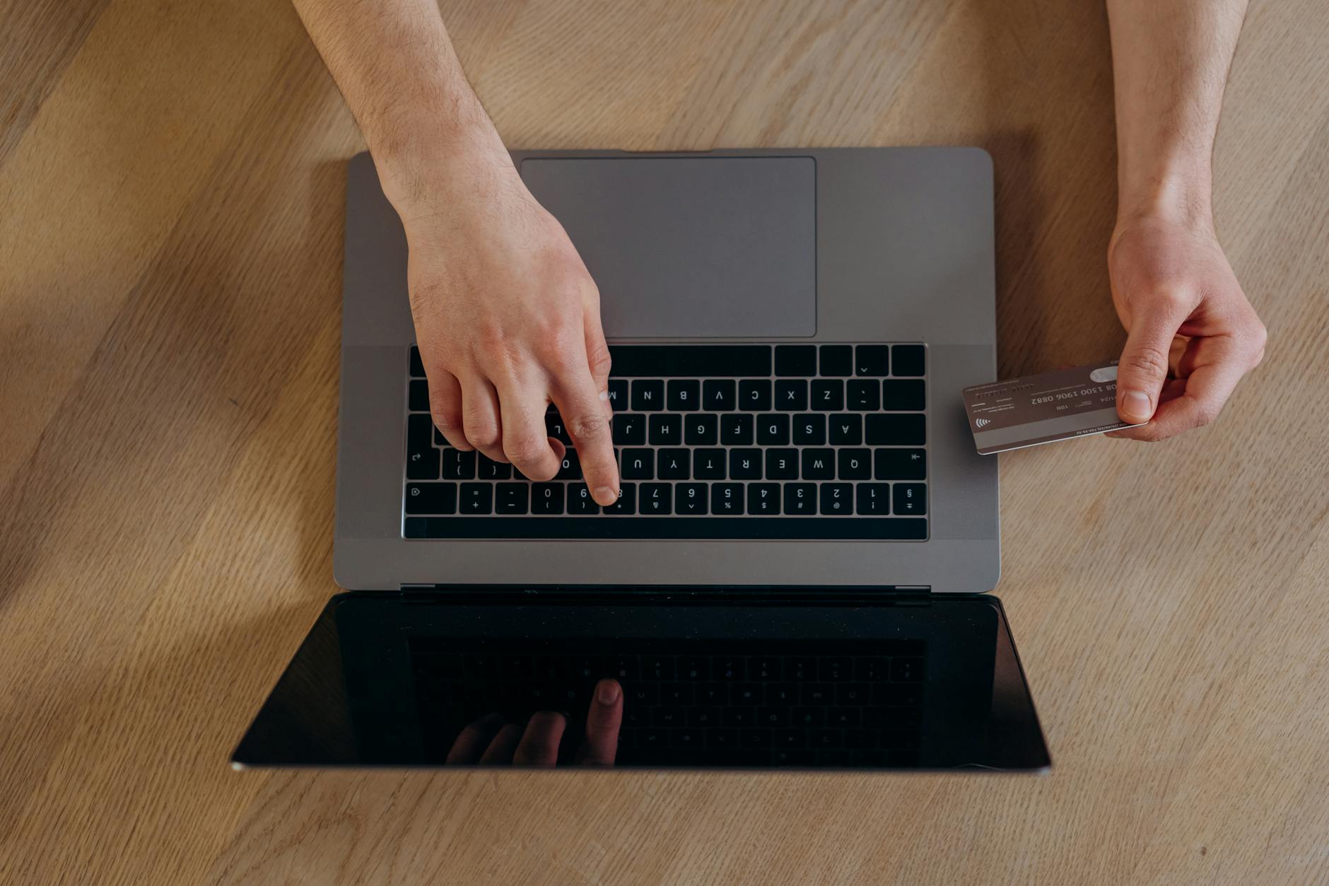 A student holding a credit card while checking a phone.