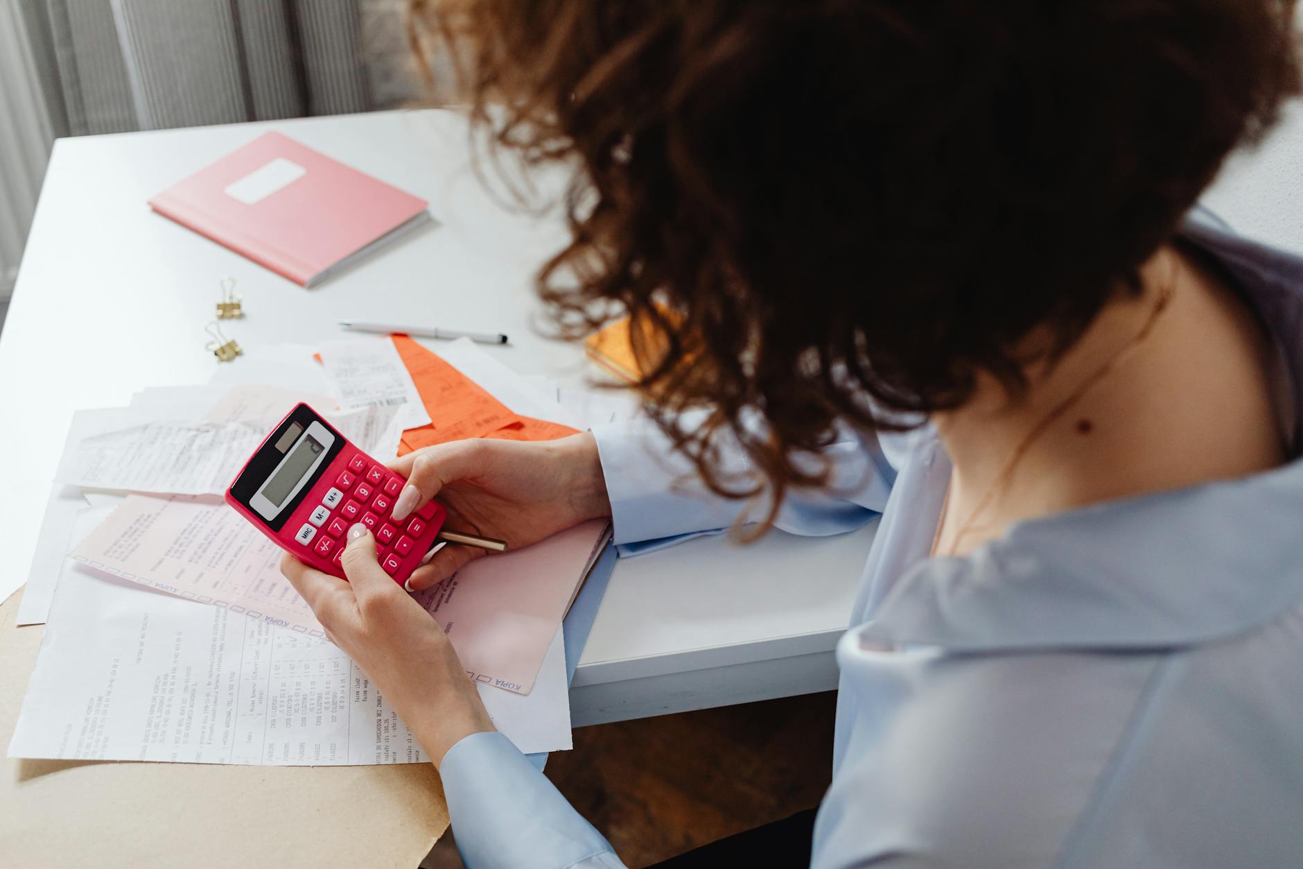 A homeowner reviewing refinance numbers on a phone near paperwork.