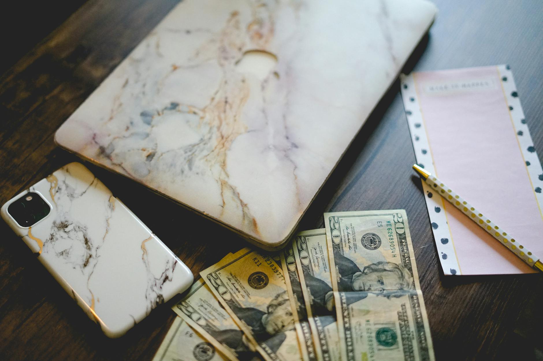 Cash, a phone, and a notebook arranged for a household budget review.