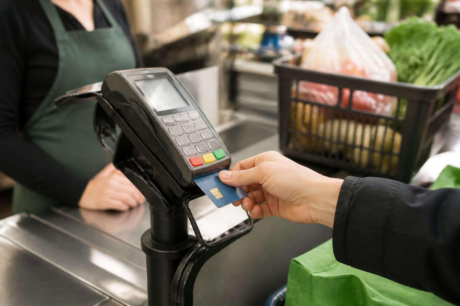 A shopper inserting a chip card at a grocery checkout terminal.
