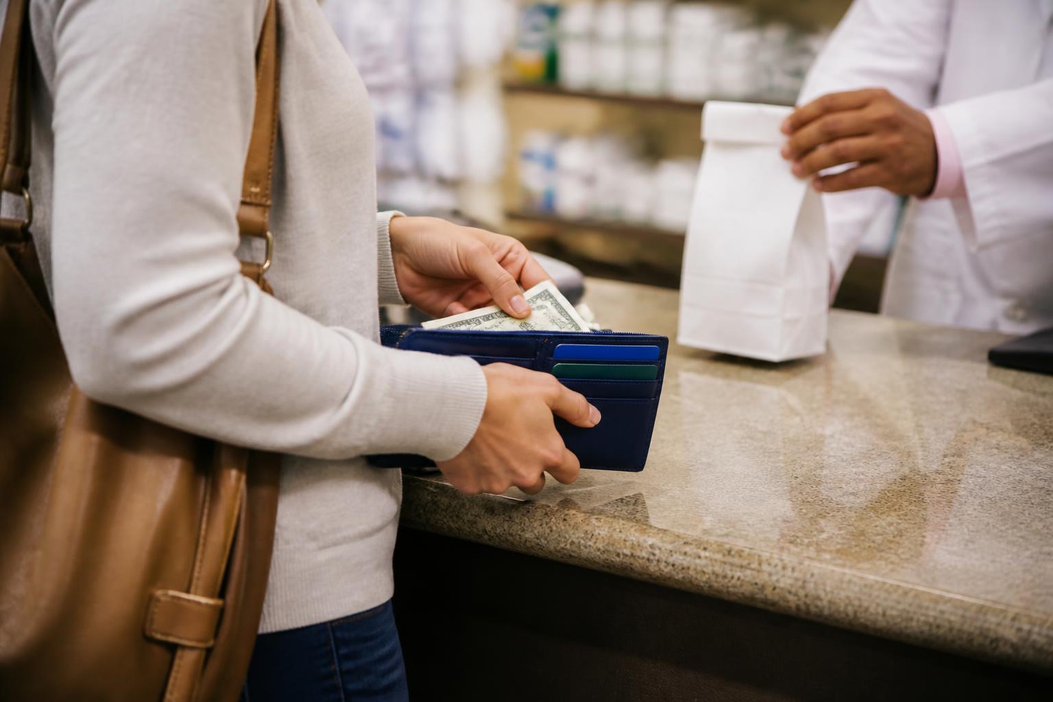 A customer picking up a prescription while holding emergency cash.