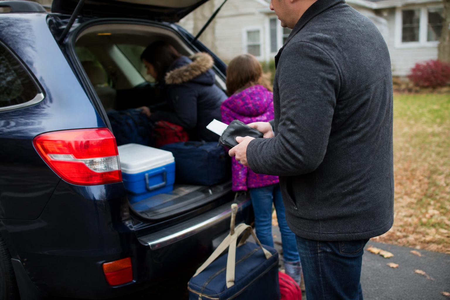 A family loading a car for Thanksgiving travel while setting aside gas savings.