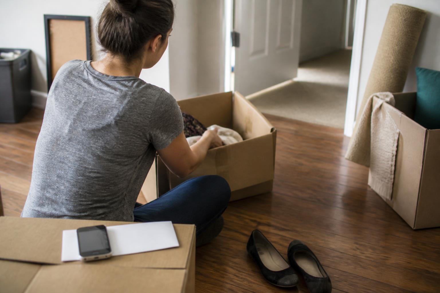 A new graduate unpacking boxes while a loan reminder sits nearby.