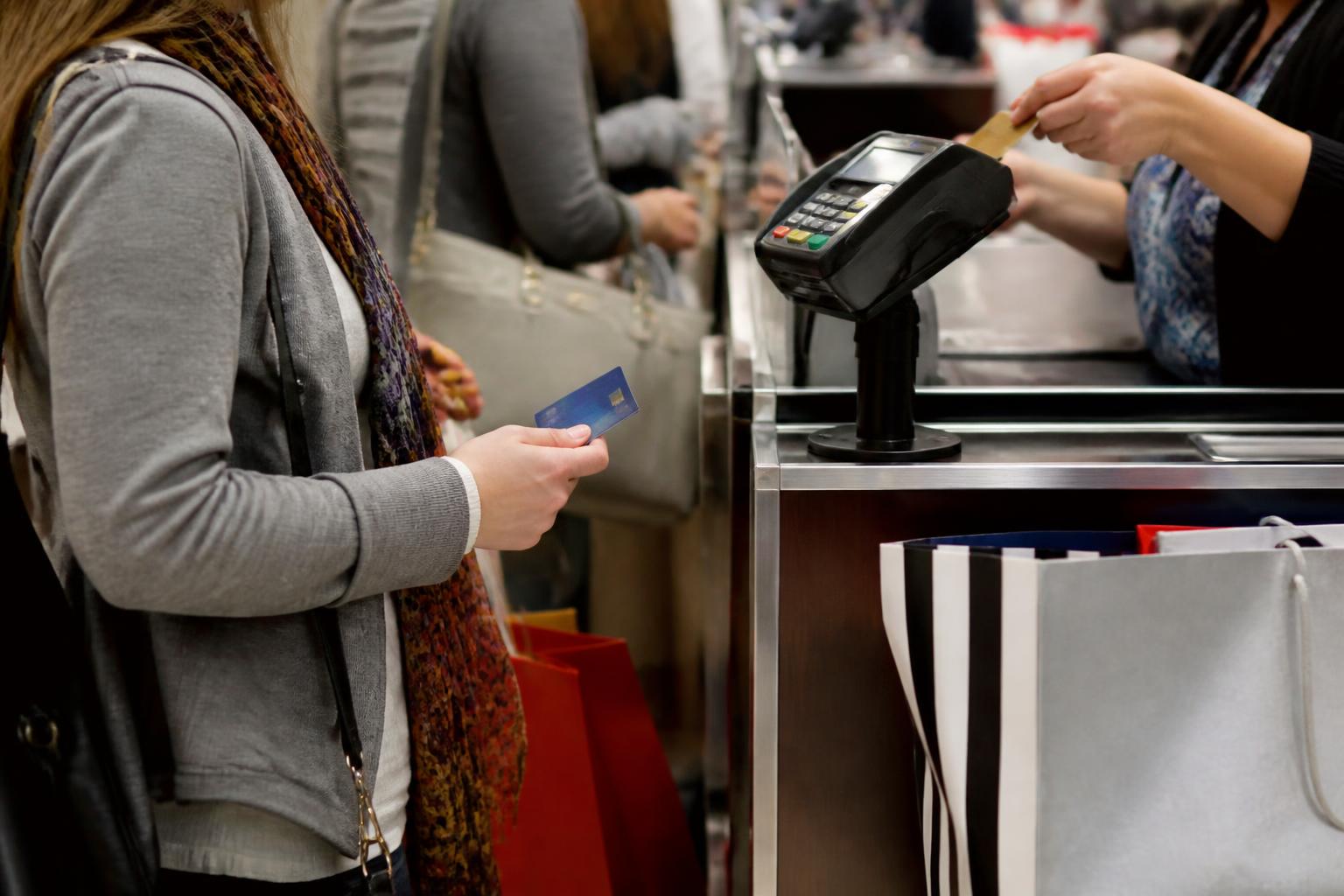 A shopper holding a chip card while waiting in a busy checkout line.