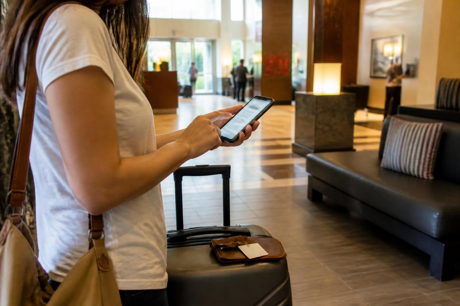 A traveler setting a blurred card alert beside luggage in a hotel lobby.
