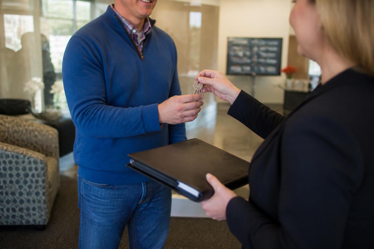 A homeowner leaving a refinance consultation with house keys and a closed folder.