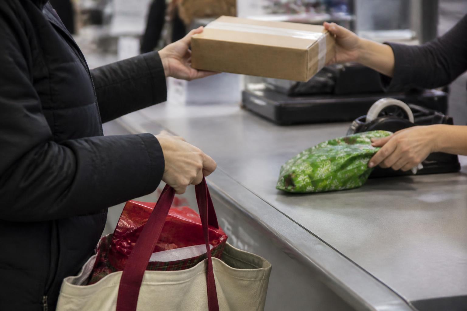 A shopper shipping one package while keeping a wallet closed before the deadline.