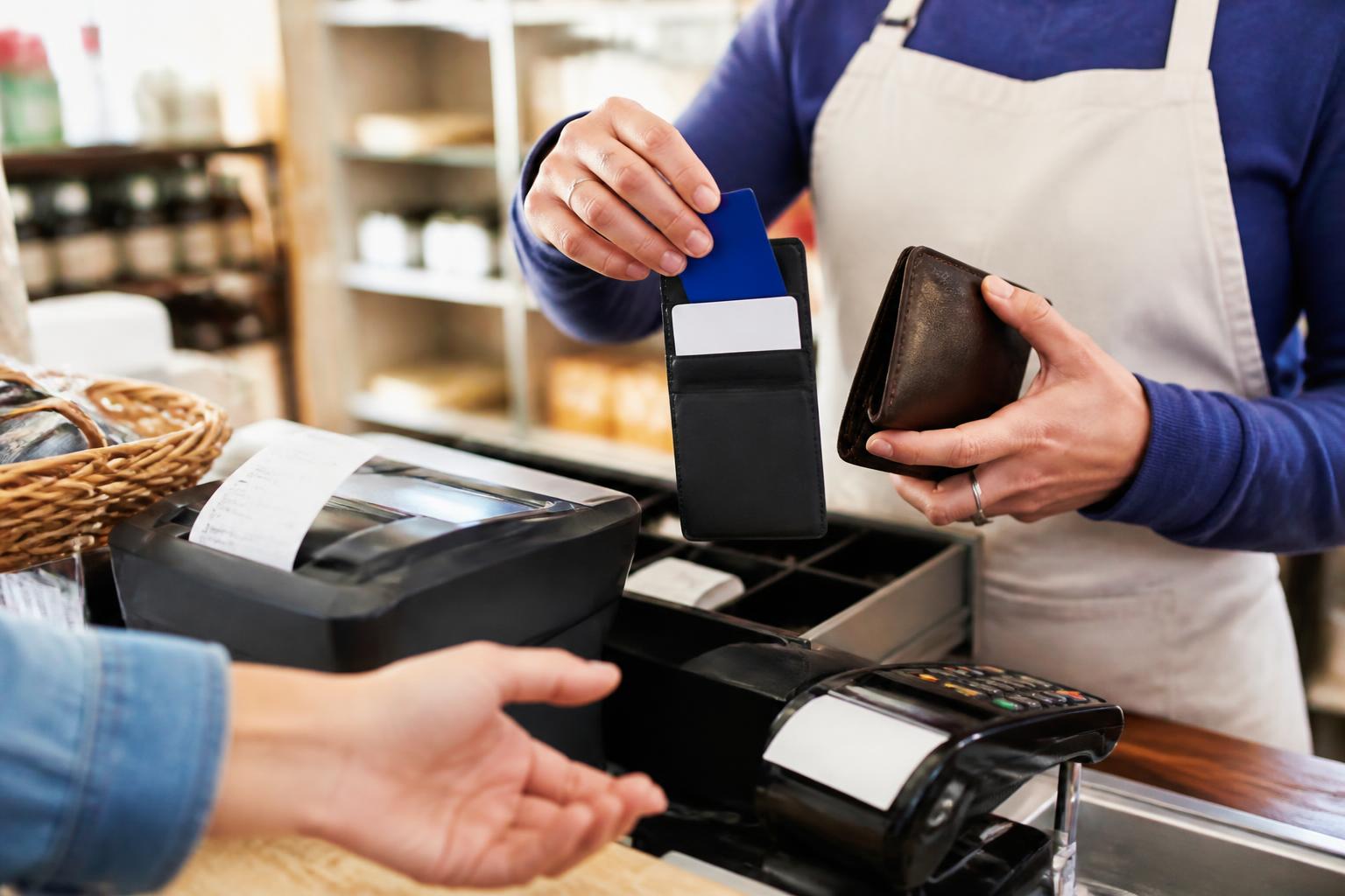 A small shop owner keeping business and personal cards separate at checkout.