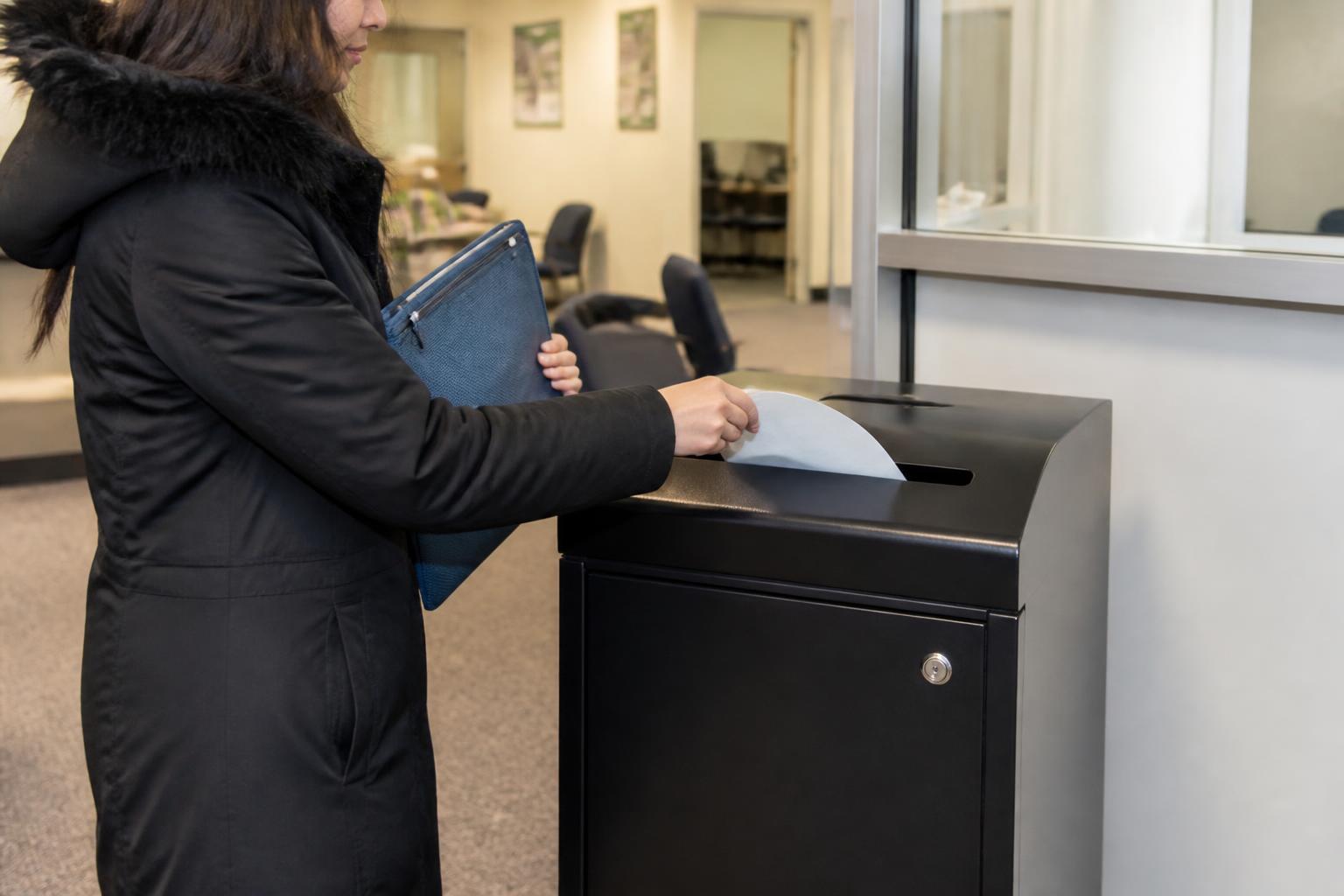 A taxpayer using a locked shred bin in a tax-prep lobby.