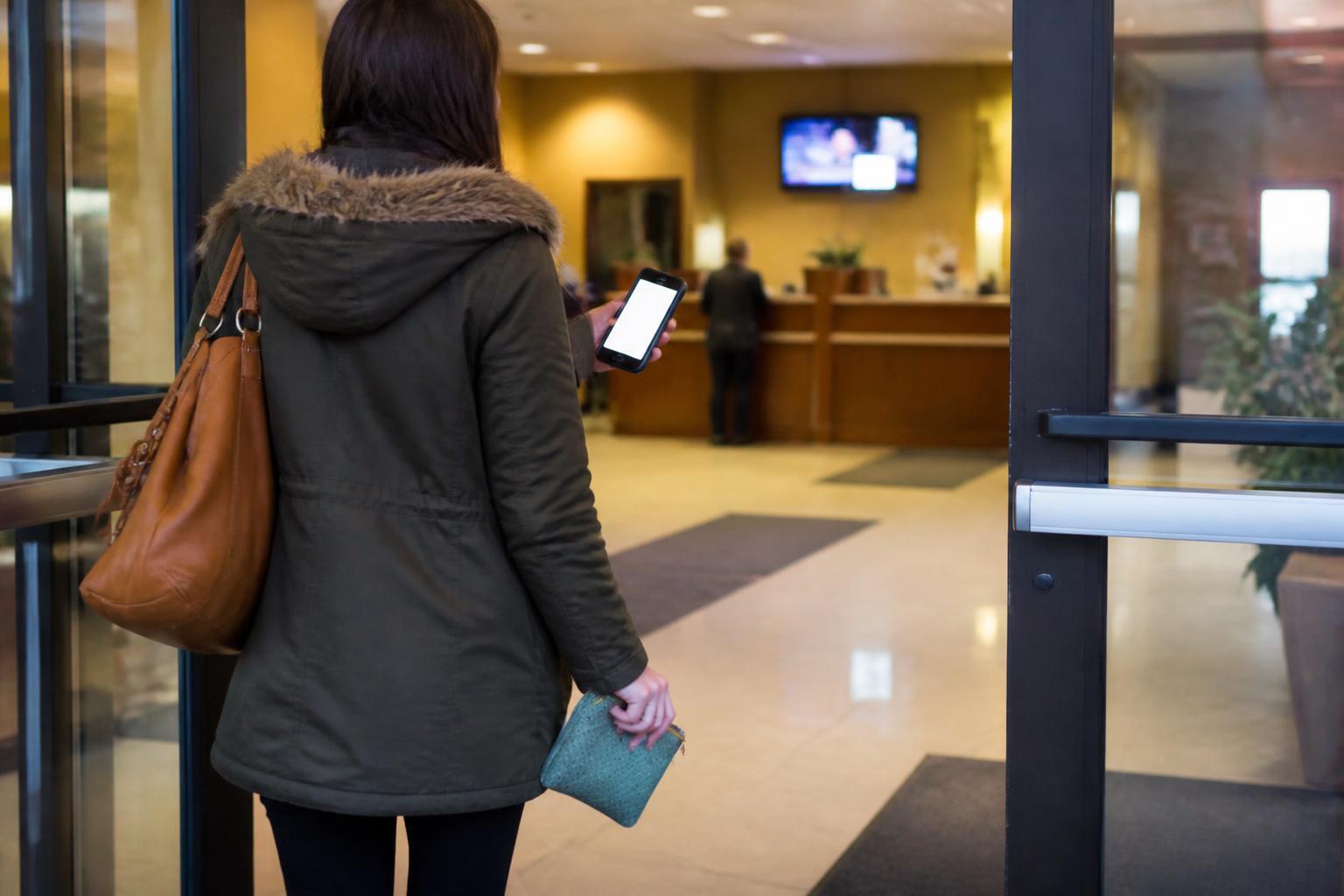 A saver entering a credit union while checking a blurred balance alert.