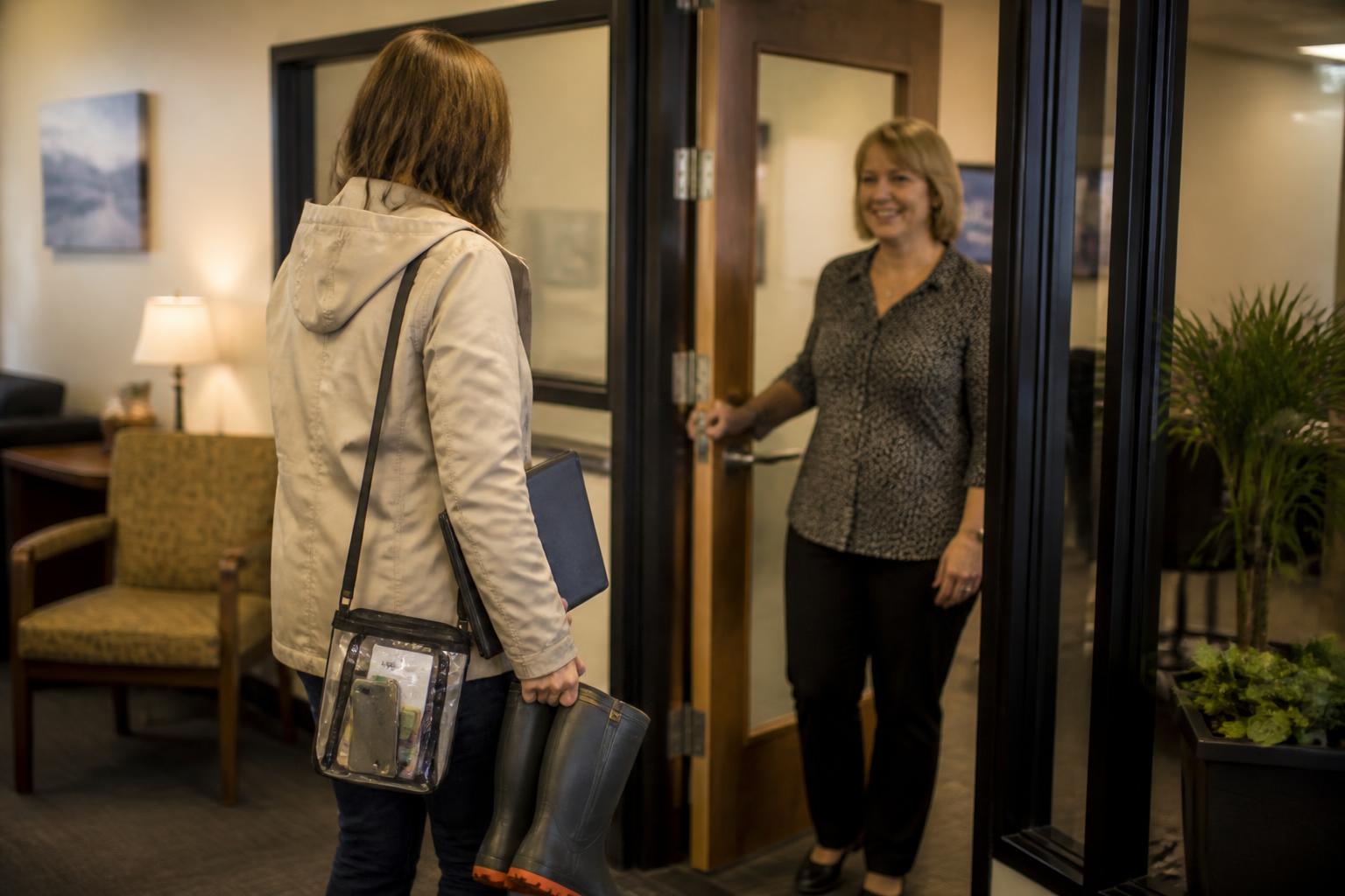 A homeowner entering an insurance office with rain boots and a waterproof pouch.