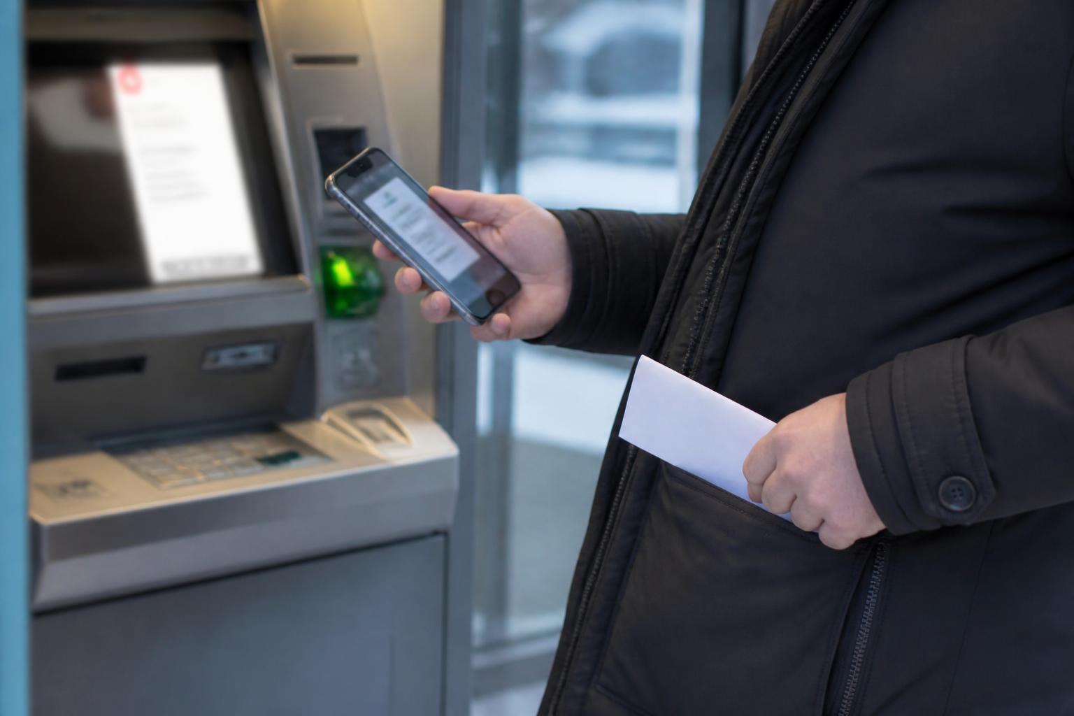 A filer checking a blurred refund status alert near an ATM.