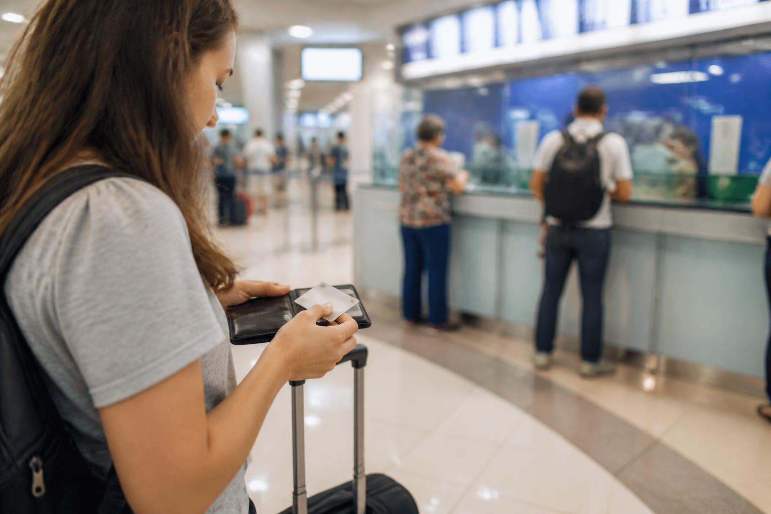 A traveler checking a payment card while walking through an airport concourse.
