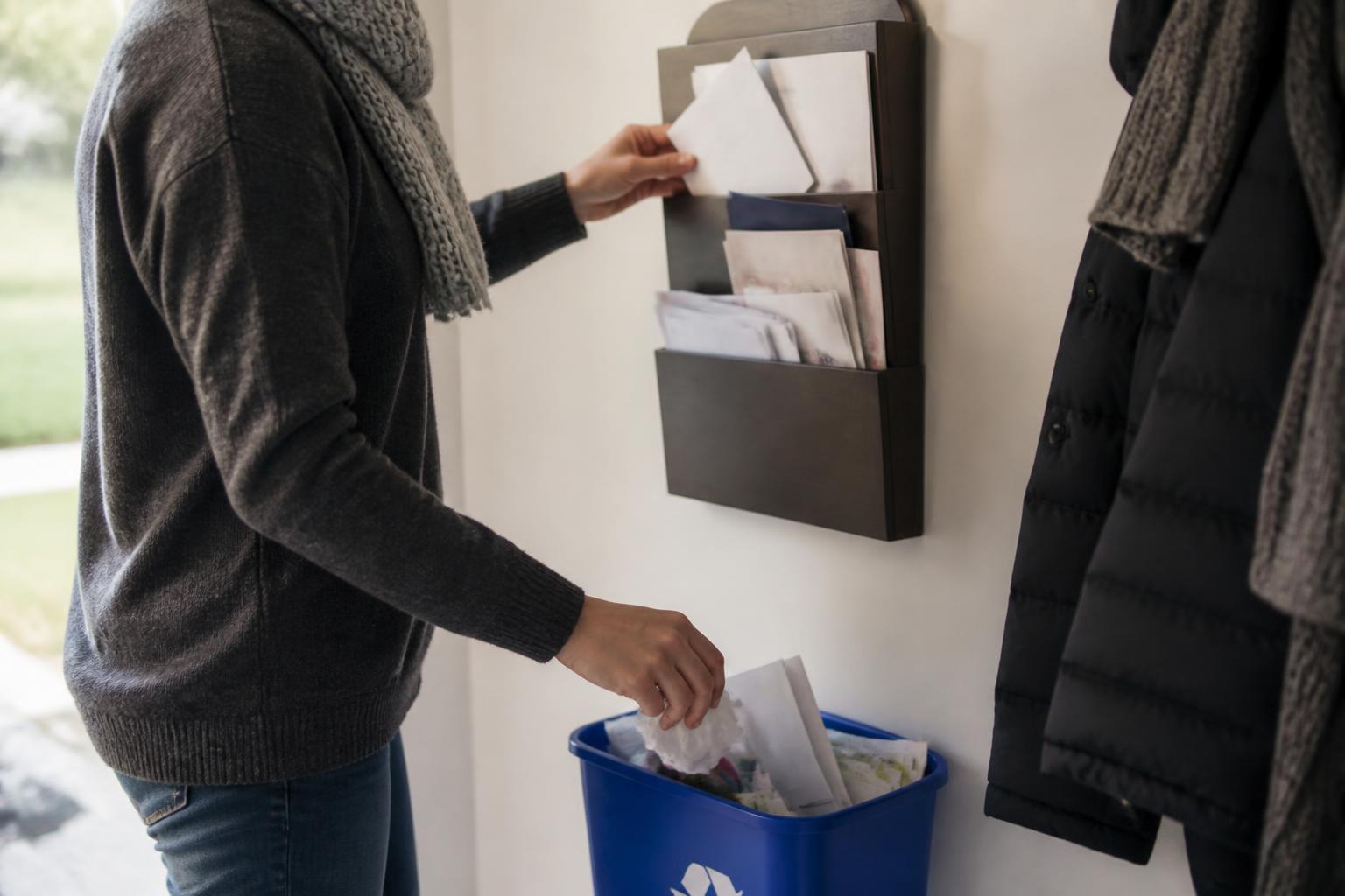 A person sorting household mail into an entryway wall organizer.