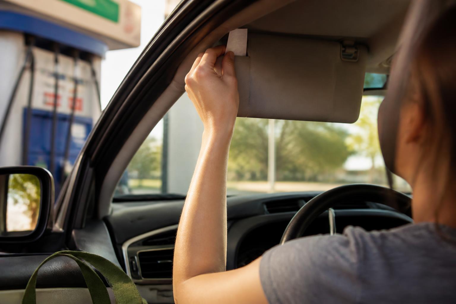 A driver saving a gas receipt at a gas station.