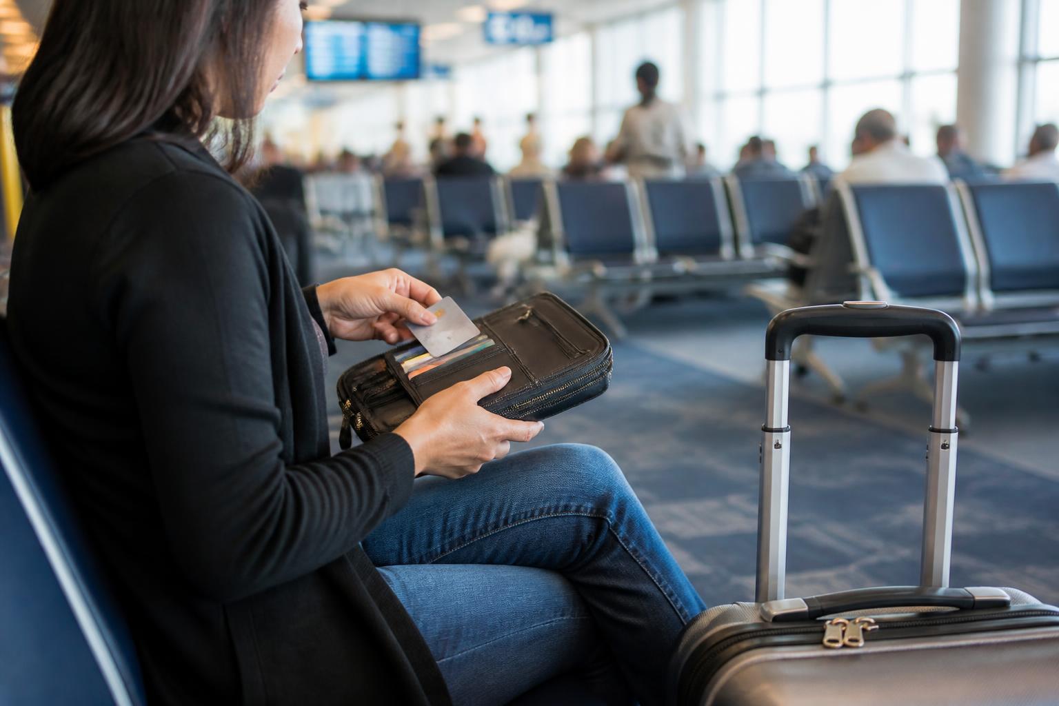 A traveler checking a wallet and card at an airport gate.