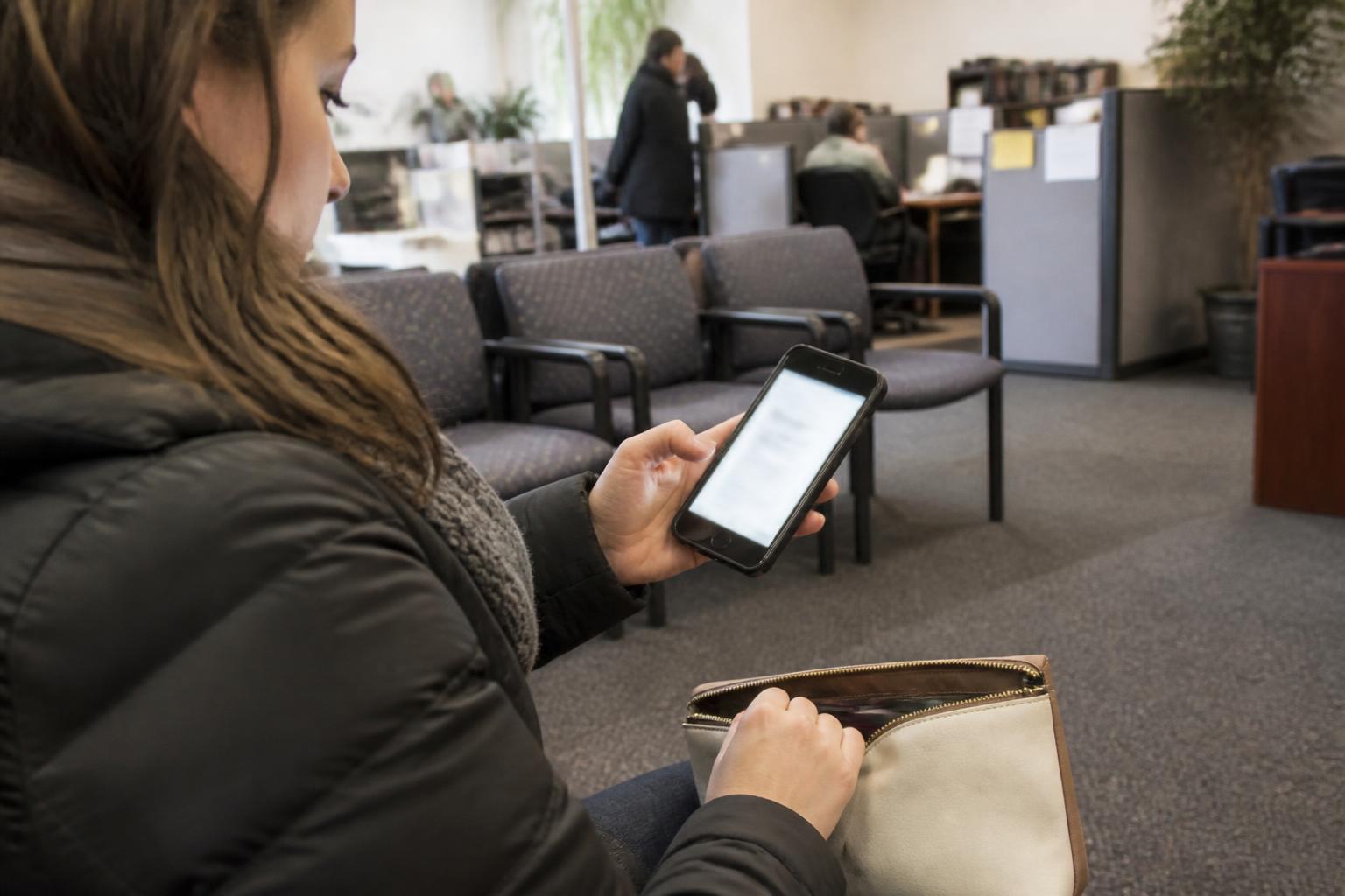 A filer checking a refund-status alert in a tax-prep office lobby.