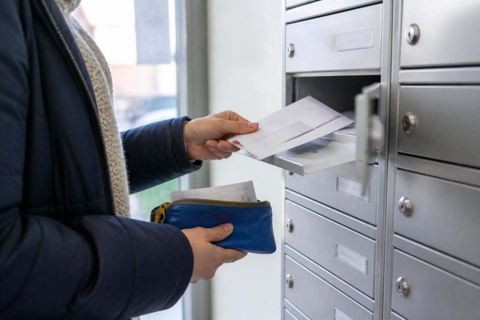 A tenant retrieving tax mail from an apartment mailbox.
