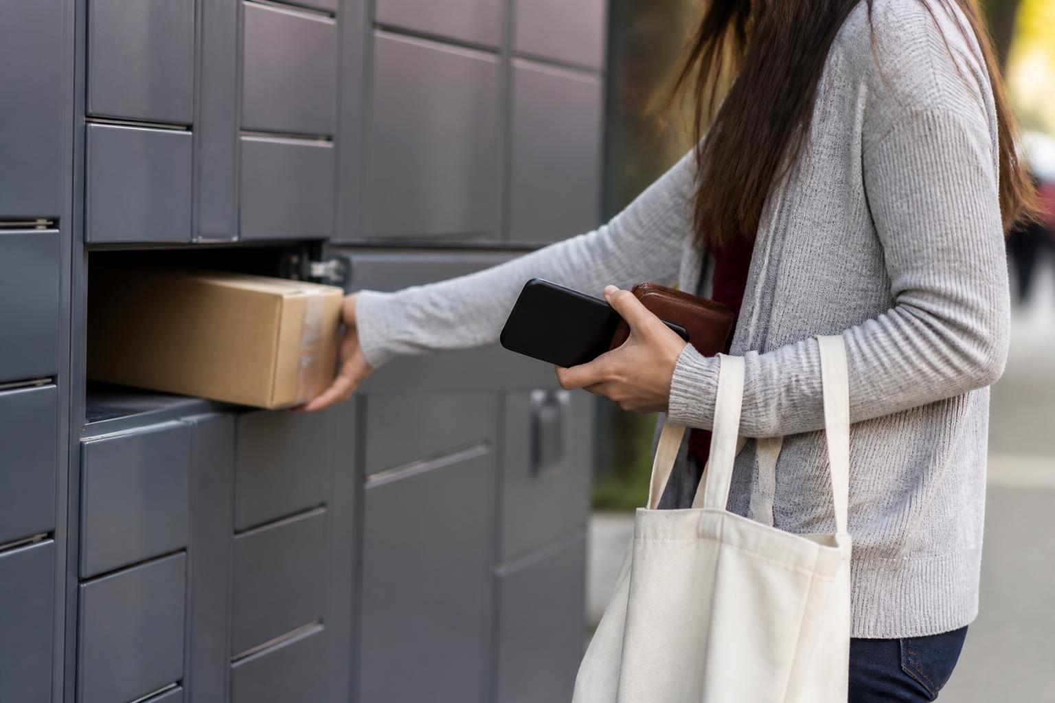 A shopper using a package locker while checking shipping and return logistics.