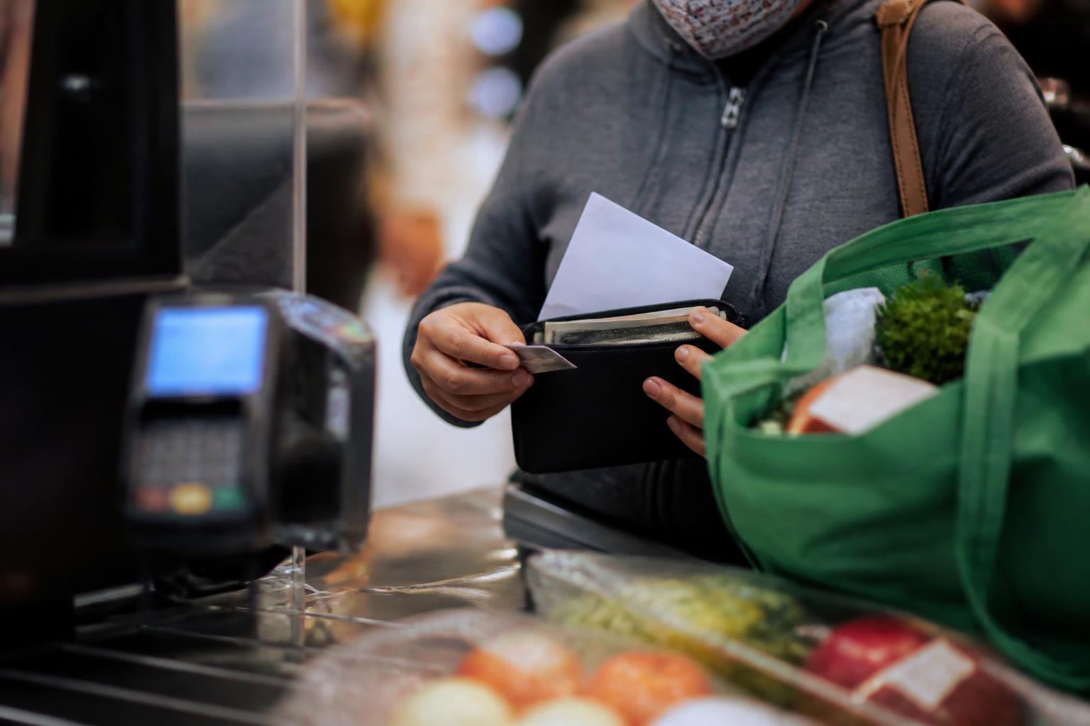 A shopper separating grocery cash during early pandemic relief planning.