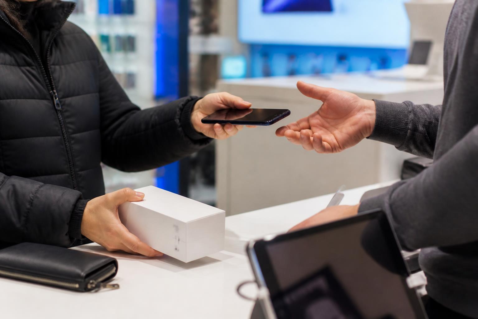 A customer reviewing device debt at a wireless store counter.
