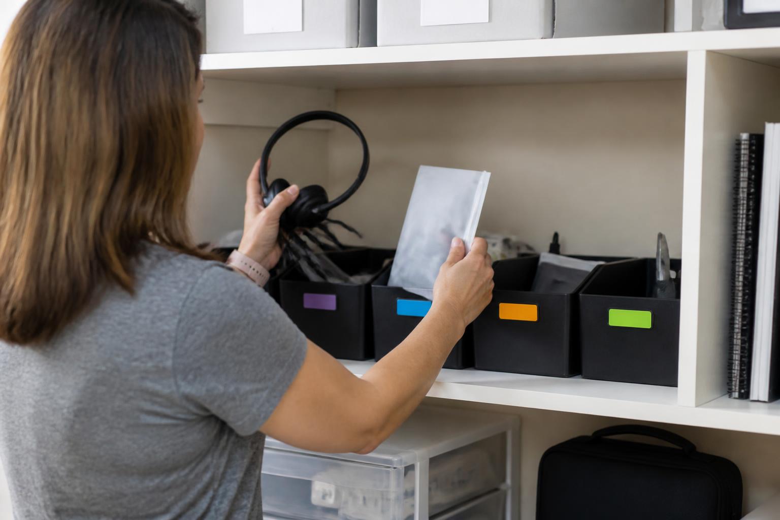 A remote worker organizing equipment and expense records on a home shelf.