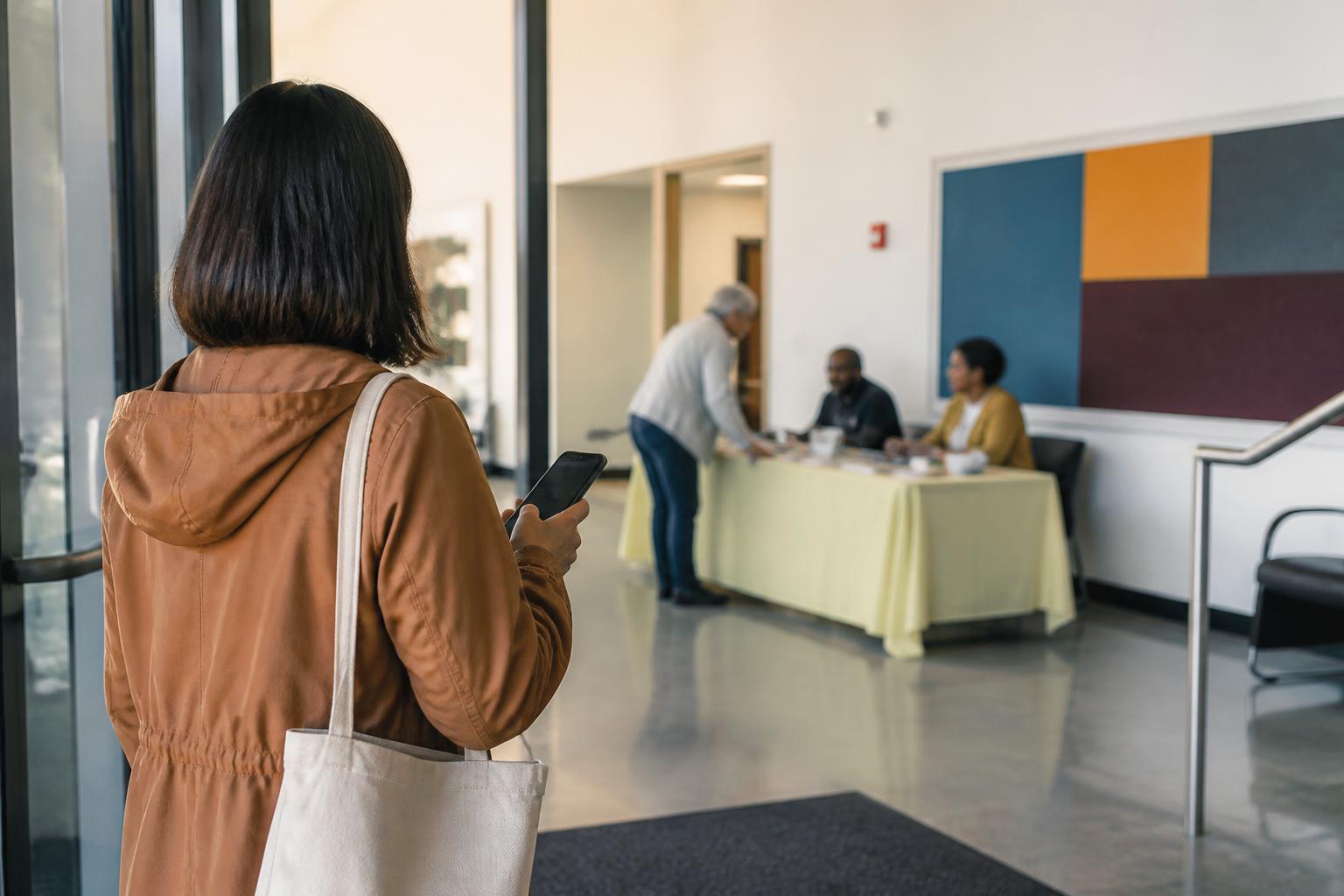 A donor checking a phone before approaching a community volunteer table.