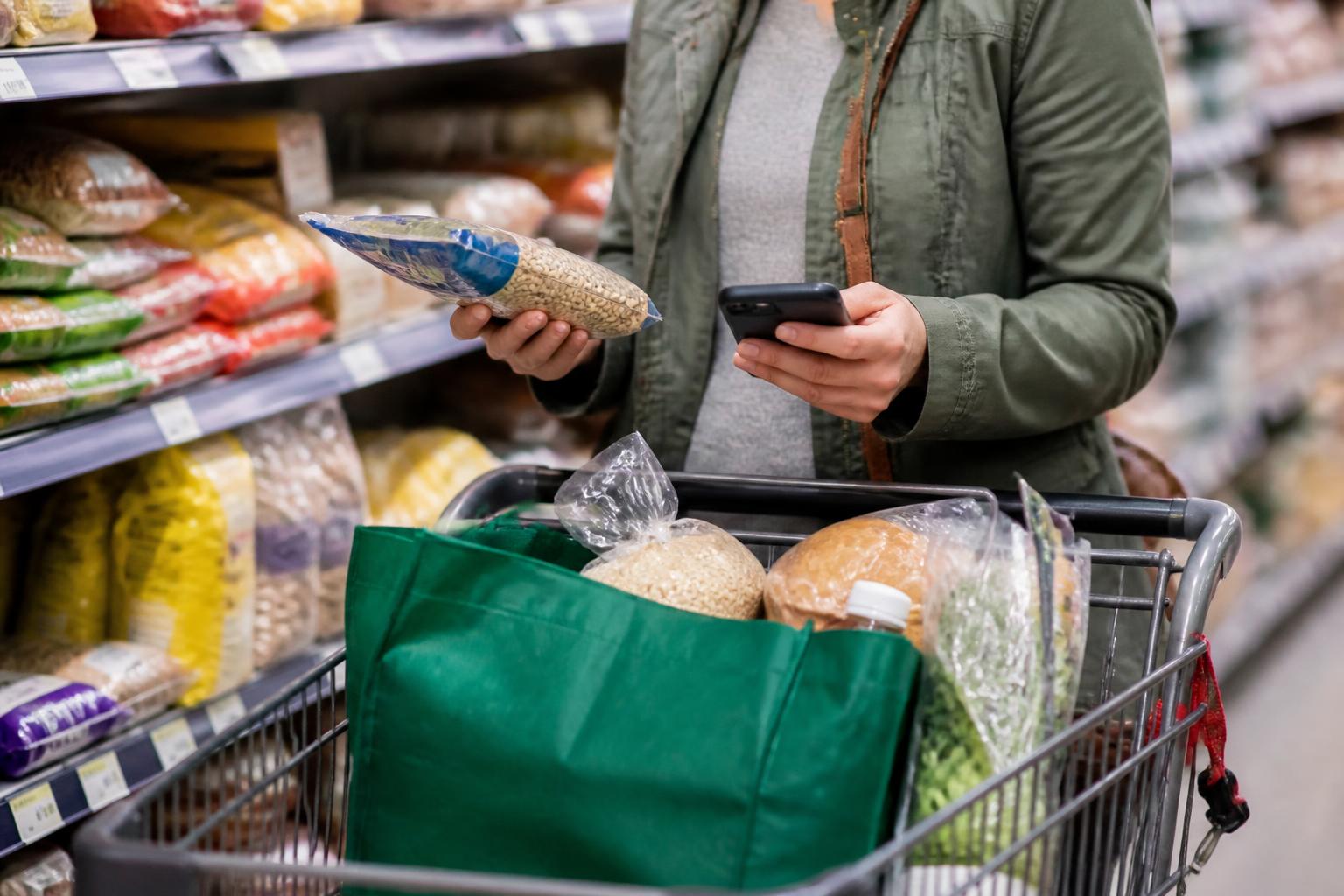 A shopper comparing grocery staples after household relief changed.