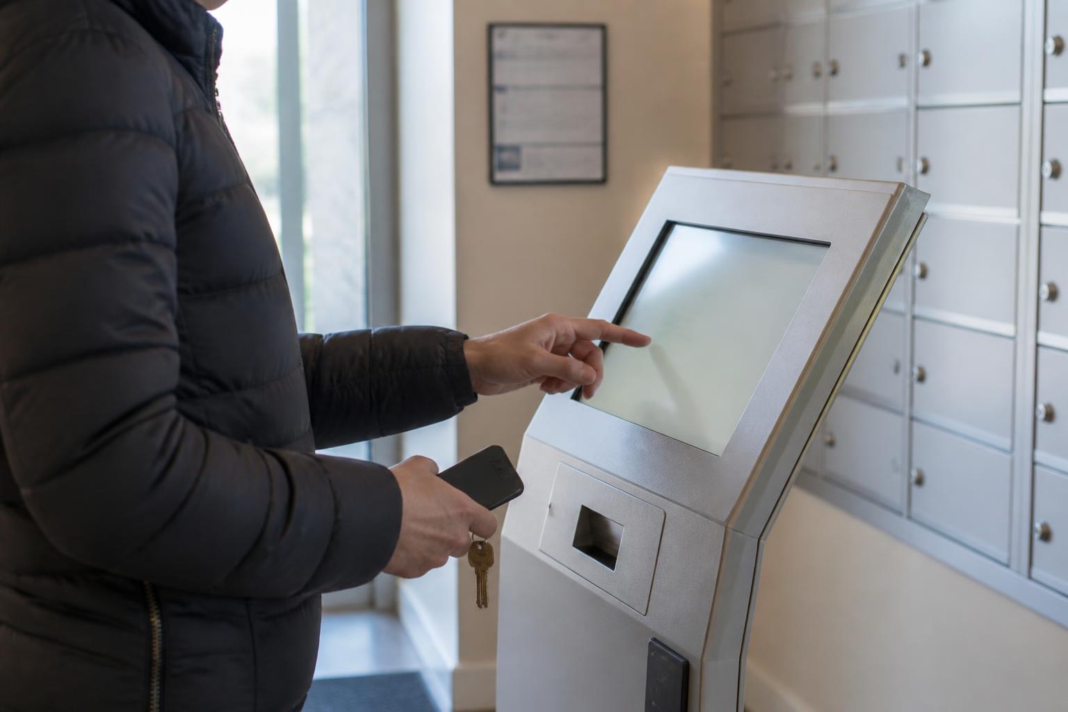 A resident using an apartment payment kiosk after rent and utility planning.