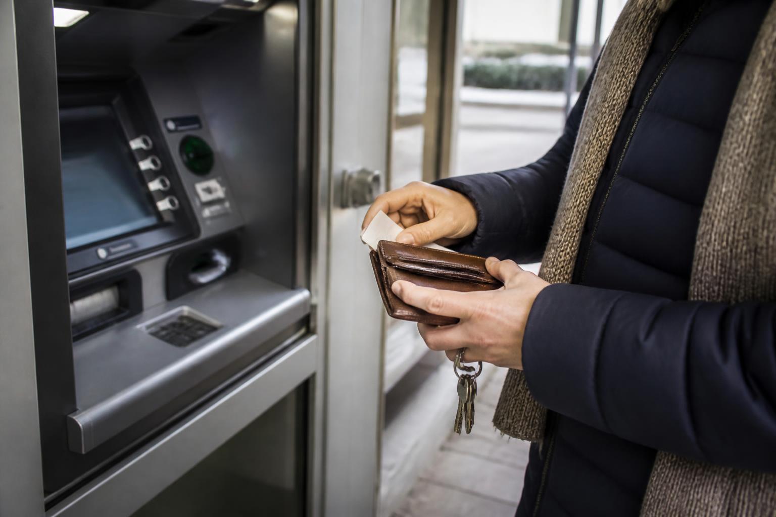 A customer placing a face-down ATM receipt into a wallet.
