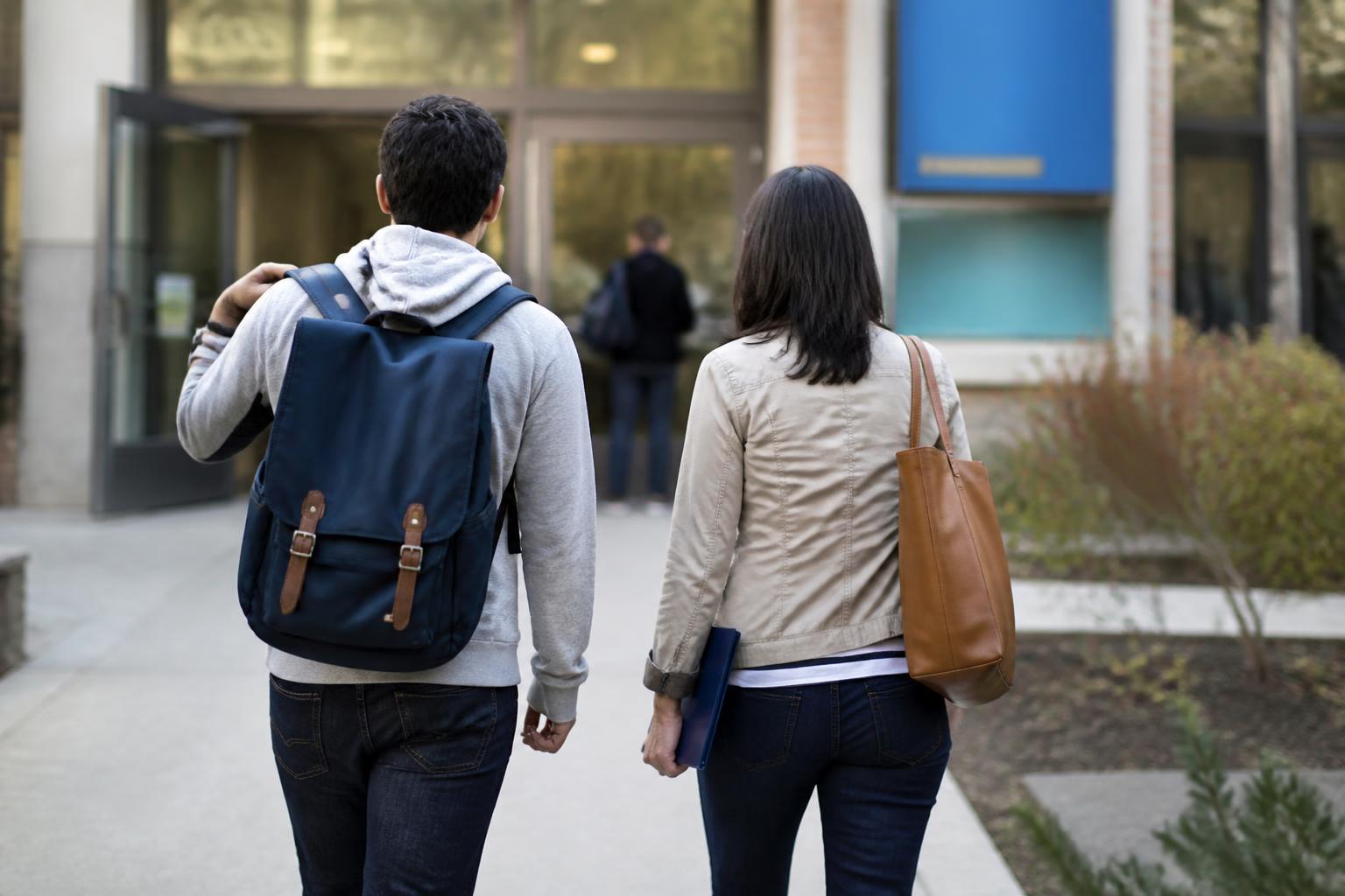 A student and parent walking toward a campus financial-aid office.