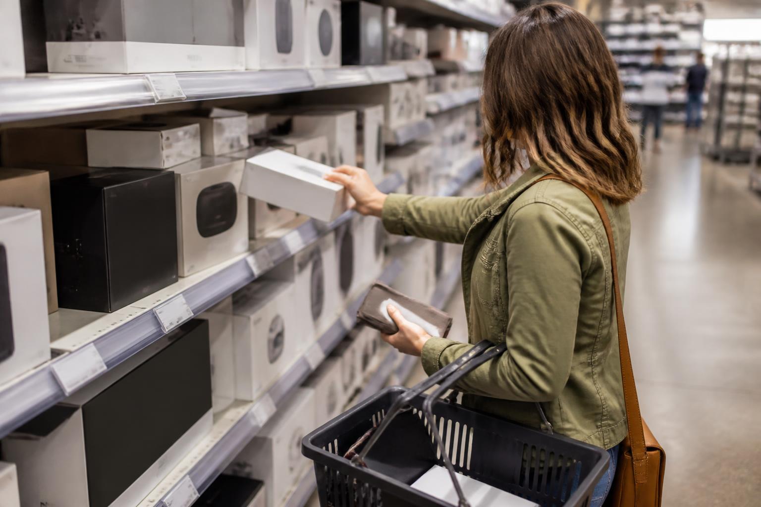 A shopper putting a plain electronics box back on a store shelf.