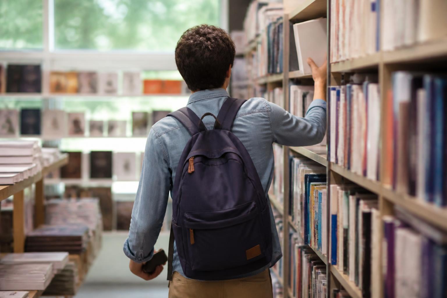 A borrower returning an unbranded textbook to a campus store shelf.