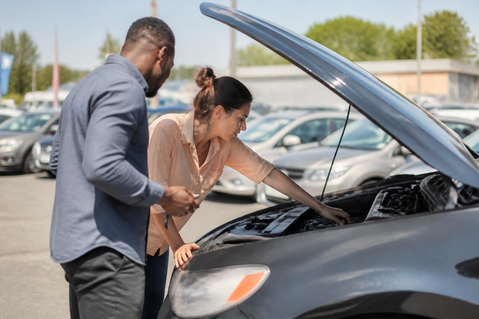 A buyer inspecting a car engine before a Labor Day purchase.