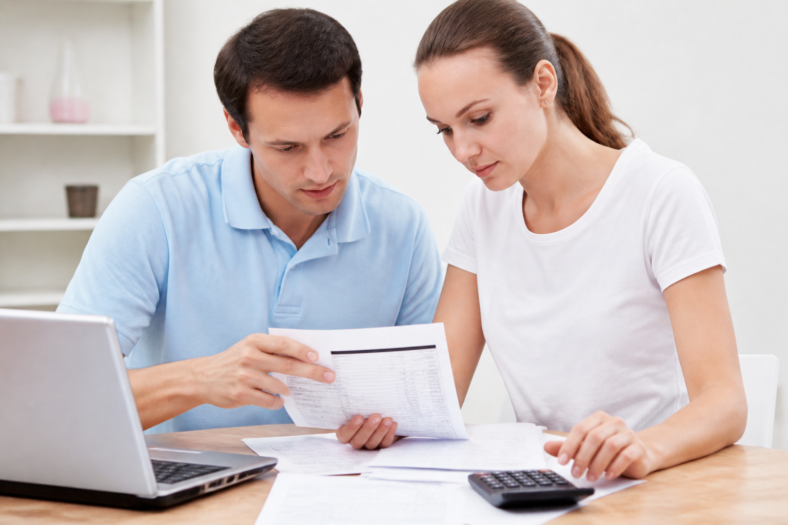 A smiling couple with a laptop and paperwork.